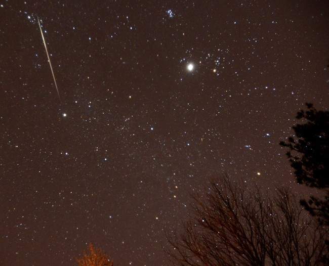 In this Thursday Dec. 13, 2012 file photo, a meteor streaks across the sky during the annual Geminid meteor shower.