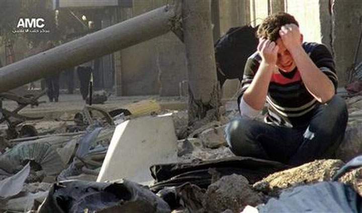 A Syrian man mourns as he sits in the rubble of buildings following a Syrian government airstrike in Aleppo, Syria.