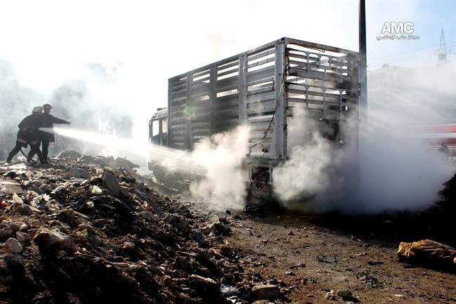In this citizen journalism image provided by Aleppo Media Center, AMC, which has been authenticated based on its contents and other AP reporting, firefighters hose down burning vehicles after a Syrian aircraft pummeled masaken hanano, an opposition neighborhood in the northern city of Aleppo, Syria, Sunday, Dec. 22, 2013. 