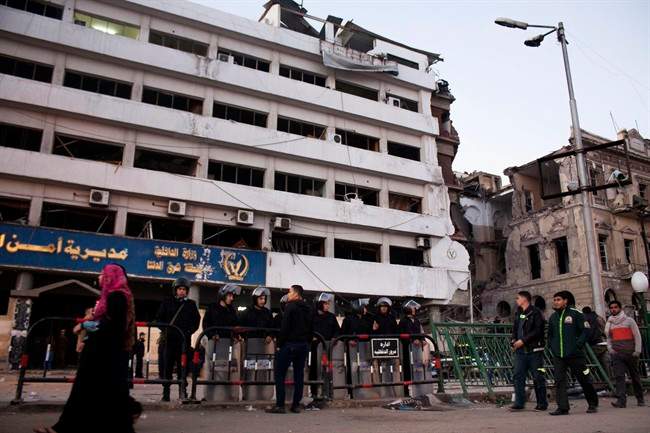 Egyptian policemen stand guard at the scene of a powerful explosion believed to be a car bomb at a police headquarters building that killed at least a dozen people, wounded more than 100, and left scores buried under the rubble, in the Nile Delta city of Mansoura, 110 kilometers (70 miles) north of Cairo, Egypt, Tuesday, Dec. 24, 2013. 