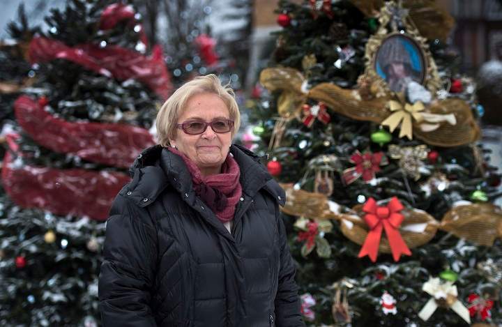 Mayor Colette Roy-Laroche stands next to Christmas trees placed in front of the church Sunday, December 8, 2013 in Lac-Megantic, Que., one for every one of the 47 victims of an oil tanker train derailment that burned the most part of downtown Lac-Megantic in July.