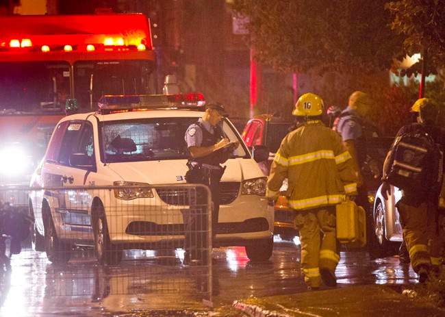 Police and firefighters work at the rear of an auditorium where a gunman shot and killed at least one person during the PQ victory rally on September 5, 2012, in Montreal. 