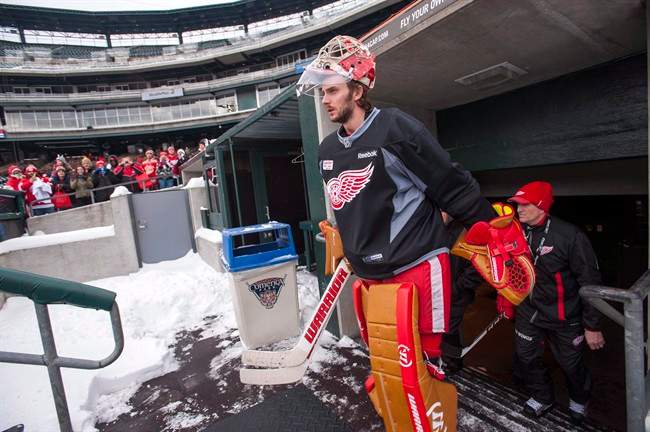 Detroit Red Wings goaltender Jonas Gustavsson walks out of the dugout to the outdoor hockey rink for practice at Comerica Park, home of the Detroit Tigers baseball team, Wednesday, Dec. 18, 2013, in Detroit.