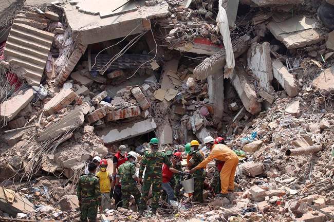 Workers try to release two bodies trapped in the rubble of collapsed Rana Plaza garment factory building in Savar, near Dhaka, Bangladesh, April 30, 2013. More than 1,100 garment workers were killed in the Bangladesh factory collapse in April.