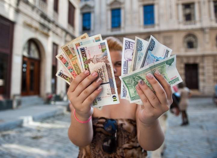 A Cuban shows Cuban Pesos CUP (Left  hand) and Convertible Pesos CUC (Right hand), on October 22, 2013 in Havana. 