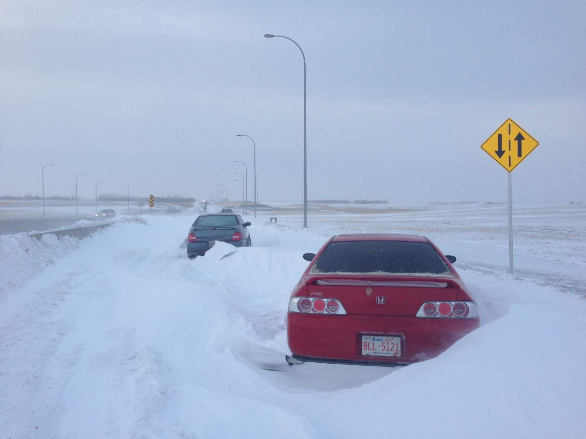 Cars sit stranded by the side of the road on Metis Trail during a winter storm in Calgary on Tuesday, December 3rd, 2013. (The Canadian Press)