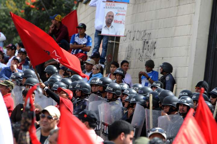 Honduras:Riot policemen stand guard as supporters of Honduran presidential candidate for the Libertad y Refundacion (LIBRE) party, Xiomara Castro, protest against the results of the presidential election in Tegucigalpa, on Dec. 1, 2013. Officials said late Saturday that conservative Juan Orlando Hernandez defeated his rival, leftist presidential hopeful Xiomara Castro, by eight percentage points in the Nov. 24 election. Castro rejected the results of the election and called for mass protests claiming there was a “monstrous fraud” in the crime-stricken Central American country.  (Photo credit: Getty Images)
