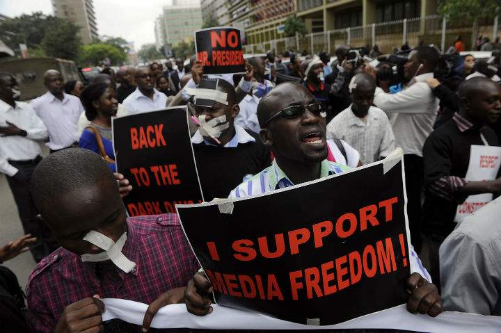 Kenyan journalists, some covering their mouths with tape, hold signs during a protest against a controversial bill that they say would allow the government greater control over the press in Nairobi on December 3, 2013. (Photo by: Simon Maina/AFP/Getty Images)