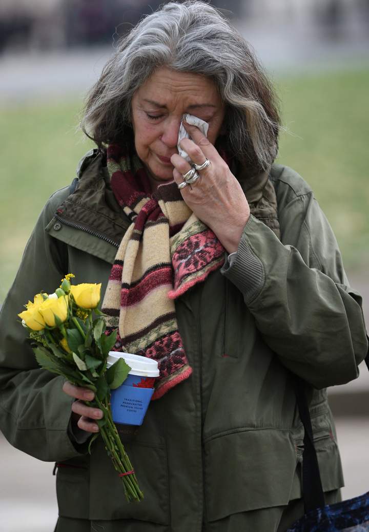 London:Joanna Vignola weeps before placing a floral tribute at the foot of a statue to Nelson Mandela in Parliament Square on December 6, 2013 in London, England. (Photo credit: Getty Images)