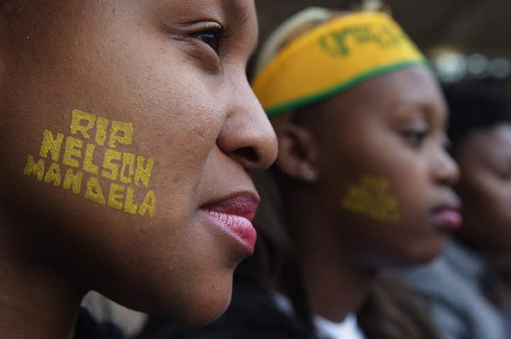 Two young women attend the official memorial service for former South African President Nelson Mandela at FNB Stadium Dec. 10, 2013 in Johannesburg, South Africa. Over 60 heads of state have travelled to South Africa to attend a week of events commemorating the life of Nelson Mandela. (Photo credit: Getty Images)
