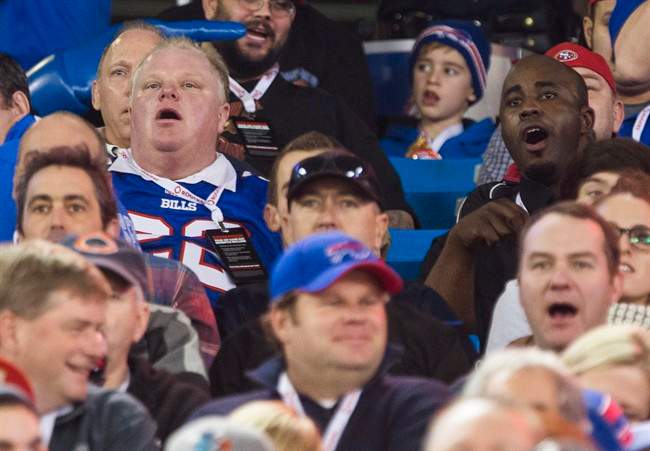 Toronto Mayor Rob Ford and his driver Jerry Agyemang, right, watch the Buffalo Bills play the Atlanta Falcons during the first half of NFL action in Toronto, Sunday December 1, 2013. THE CANADIAN PRESS/Mark Blinch