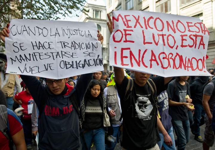 Mexico City:People hold signs reading, “When injustice becomes a tradition, protesting becomes a duty” and “Mexico is not in mourning, it is pissed off,” as they take part in a protest against Mexican President Enrique Pena Nieto, on the first anniversary of his government in Mexico City on Dec. 1, 2013. (Photo credit: Getty Images)