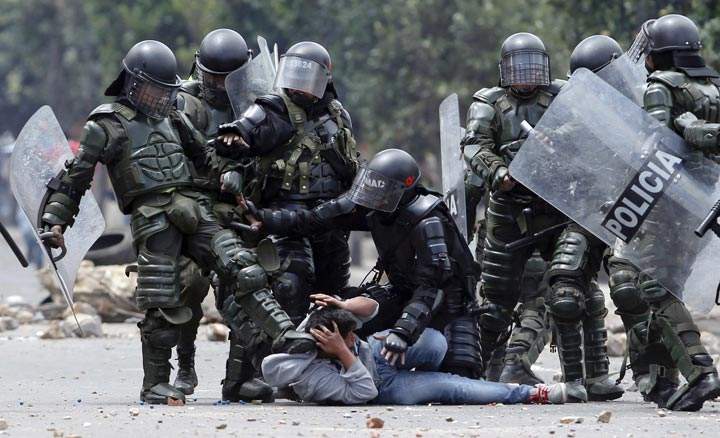 A riot police officer kicks a protester during protests in Colombia. (AP Photo/Fernando Vergara)