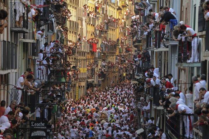 People standing on balconies look at participants as they run in front of Alcurrucen’s bulls during the first bull run of the San Fermin Festival in Pamplona, Spain. (Pedro Armestre/AFP/Getty Images)