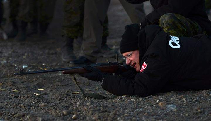 Prime Minister Stephen Harper fires a rifle in Gjoa Haven, Nunavut. (The Canadian Press /Sean Kilpatrick)