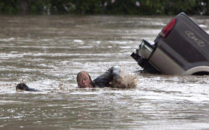 Kevan Yeats swims after his cat Momo in High River, Alberta. Yeats who gained international fame after leaping from a submerged pickup truck into Alberta floodwaters says he was surprised at how eagerly the feline took to the rushing water. (The Canadian Press/Jordan Verlage)