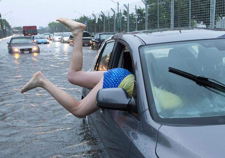 A woman gets back into her flooded car on Lakeshore Boulevard in Toronto on Monday. (The Canadian Press)