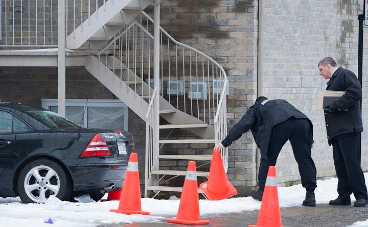 Montreal police officers survey the scene in Montreal, Monday, Dec., 28, 2009 where a man was shot, believed to be alleged mobster Nic Rizzuto Jr.