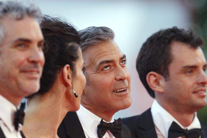 George Clooney gestures as he poses for photographers with Alfonso Cuaron, Sandra Bullock, and screenwriter Jonas Cuaron at the Venice Film Festival. (AP Photo/Andrew Medichini)