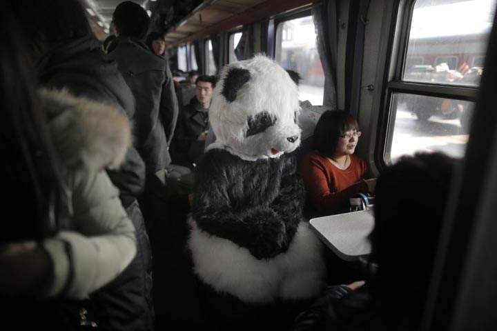 A woman wearing a panda costume sits on a train en route to Beijing. (Stringer/AFP/Getty Images)