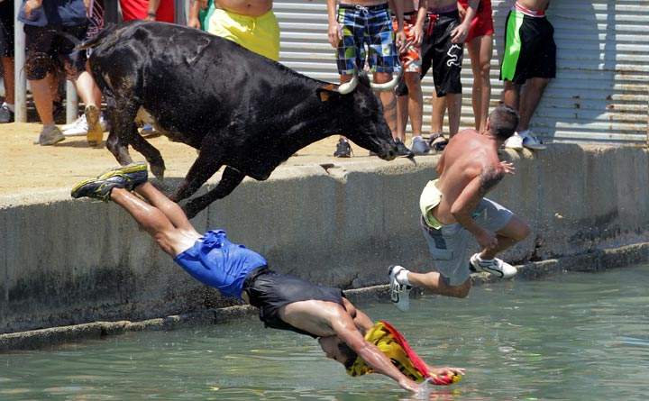 People jump with a bull into the sea during the traditional running of bulls at Denia Harbour. (Jose Jordan/AFP/Getty Images)