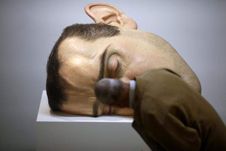 A man looks at a sculpture by Australian artist Ron Mueck  at an exhibit in Paris. (Thomas Coex/AFP/Getty Images)
.
