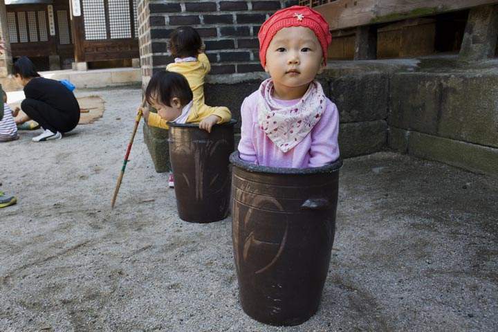 A child appears to be stuck inside a ceramic container while playing with other children at food festival in Seoul, South Korea. (Jacquelyn Martin/AFP/Getty Images)