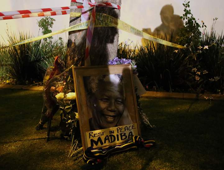 This picture shows a framed image of former South African president Nelson Mandela as people pay tributes following his death, in Johannesburg on Dec. 6, 2013.  (Photo credit: Getty Images)