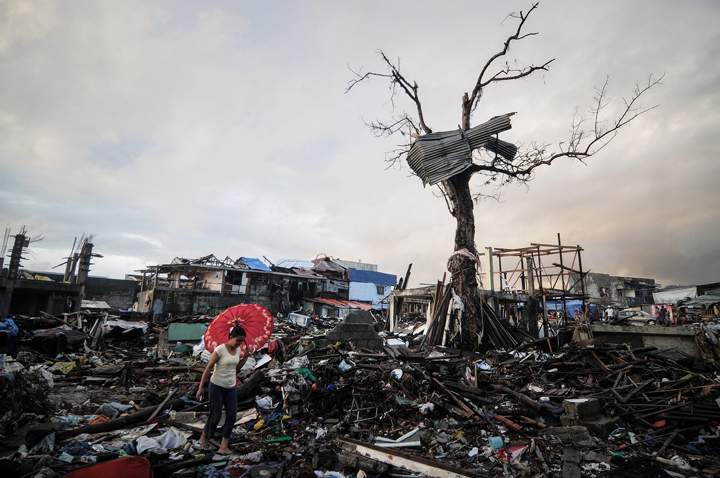 A typhoon survivor walks along debris of destroyed houses in Tacloban, Philippines, December 24, 2013. (Photo credit: AP Photo)