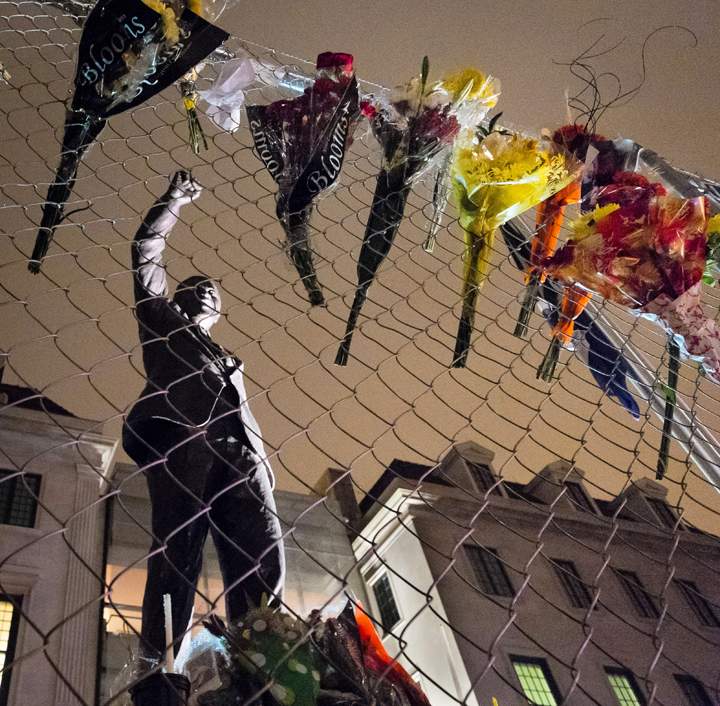 Washington:Flowers left in tribute to former South African president Nelson Mandela hang on the construction fencing in front of a statue of Mandela at the South African Embassy before daybreak in Washington Friday, Dec. 6, 2013. (Photo credit: AP Photo)