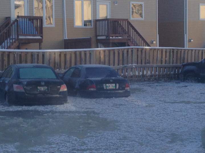 Ice forms on water surrounding cars on Morello Bay, flooded by a water main break during an extreme wind chill warning in Winnipeg.