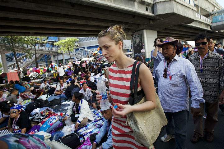 A tourist walks through an anti-government protester encampment where they are occupying a central intersection in Bangkok