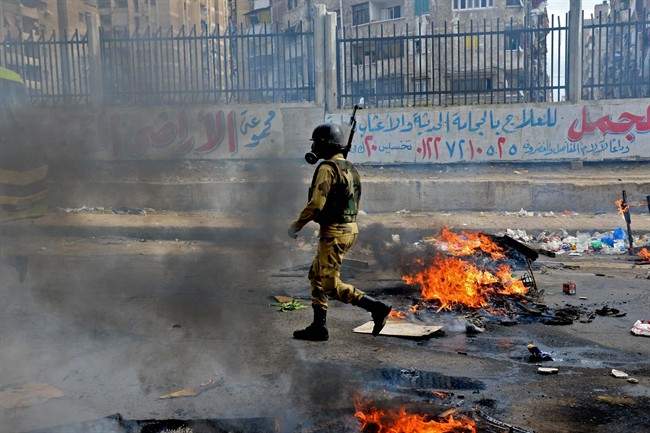 A military soldier walks through heavy smoke from clashes with supporters of Egypt’s ousted Islamist President Mohammed Mors
