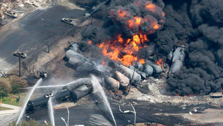 Smoke rises from railway cars that were carrying crude oil after derailing in downtown Lac Megantic, Que, Saturday, July 6, 2013. The railway safety working group want railways, shippers and producers to assume full liability for accidents and spills of dangerous goods.