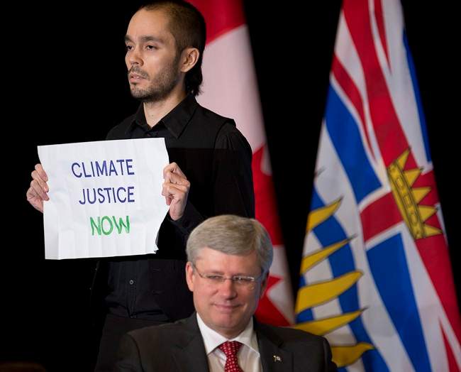 A protester rushes the stage as Prime Minister Stephen Harper speaks at the Vancouver, Board of Trade in downtown Vancouver, Monday, Jan. 6, 2014. 