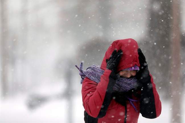 Srirupa Chatterjee holds her hood as she crosses a street Sunday, Jan. 5, 2014, in St. Louis.