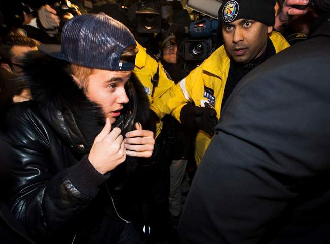 Canadian musician Justin Bieber is swarmed by media and police officers as he turns himself into city police in Toronto on Wednesday, January 29, 2014. 