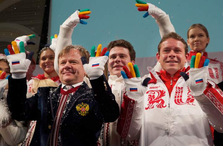 From left, jazz musician Igor Butman, pianist Denis Matsuev and former ice hockey star Pavel Bure wave their hands as they present a set of uniforms for the Russian national Olympic team for the upcoming 2014 Winter Olympic Games in Sochi, in Moscow, Russia, Thursday, Dec. 26, 2013. (Photo credit: AP Photo)