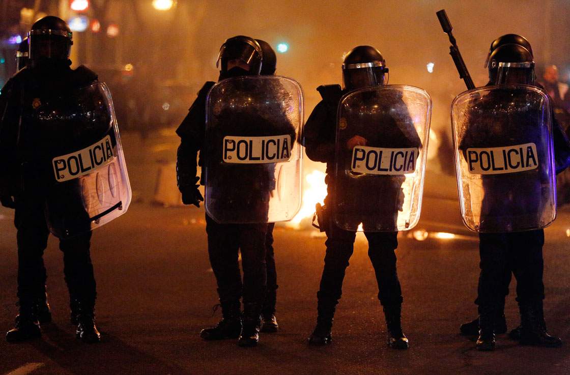 Spanish riot police officers stand in front of a fire at the end of a demonstration against government austerity measures in Madrid on February 23, 2013. Nurses, doctors, students, miners and members of Spain's 'indignant' movement against economic inequality join in the so-called 'citizens' tide' against the steep spending cuts and tax hikes imposed by the Spanish government.
