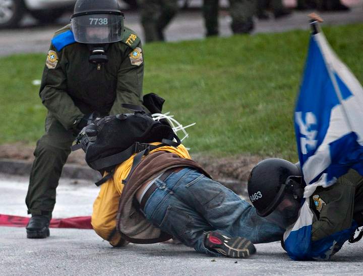 Two riot police officers tackle a demonstrator outside a Quebec Liberal Party meeting Friday, May 4, 2012 in Victoriaville, Que.