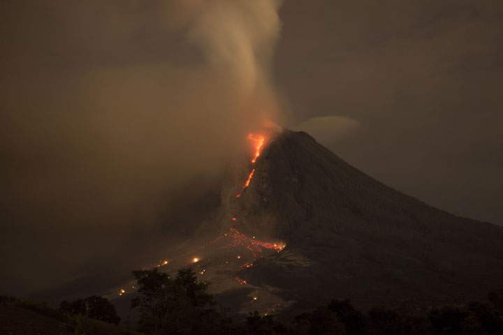 Mount Sinabung is pictured spewing smoke and lava is seen from Perteguhen village on Monday, January, 6, 2014 in Karo district, North Sumatra, Indonesia.