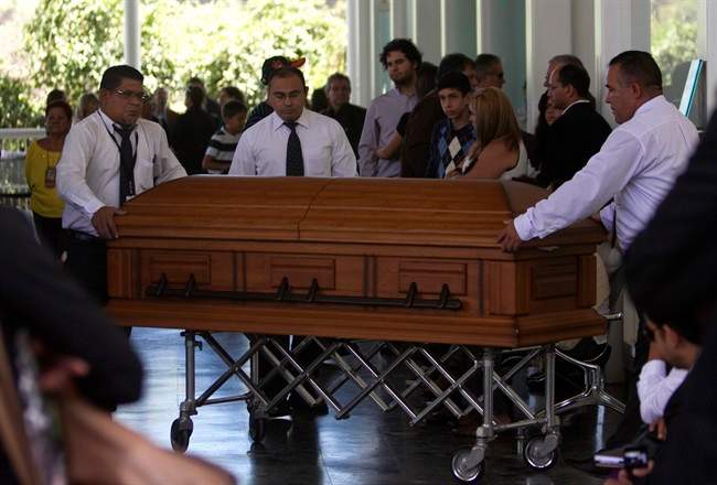 Funeral service workers push the coffin that contain the remains of Monica Spear, a popular soap-opera actress and former Miss Venezuela, into the East cemetery chapel in Caracas, Venezuela, Thursday, Jan. 9, 2014. 