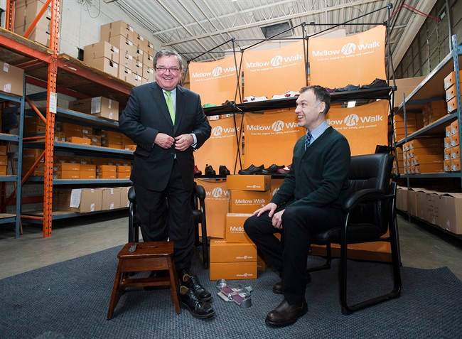 Finance Minister Jim Flaherty tries on a pair of shoes with Andrew Violi president of Mello Walk Shoes at a pre-budget press event in Toronto on Friday February 7, 2014. THE CANADIAN PRESS/Aaron Vincent Elkaim.