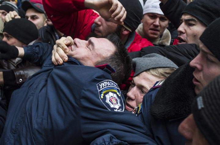 Crimean Tatars clash with a police officer , left, in front of a local government building in Simferopol, Crimea, Ukraine, Wednesday, Feb. 26, 2014. AP Photo/Andrew Lubimov