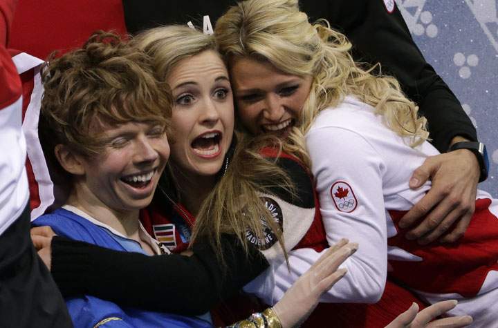 Kevin Reynolds of Canada, left, and team members react as he sits in the results area after competing in the men’s team free skate figure skating competition at the Iceberg Skating Palace during the 2014 Winter Olympics, Sunday, Feb. 9, 2014, in Sochi, Russia.