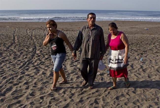 Fatima Alvarenga, left, Jose Ricardo Orellana, center, and Maria Alvarenga, the daughter and parents of Jose Salvador Alvarenga, walk on the beach after an interview near their home in the village of Garita Palmera, El Salvador, Tuesday, Feb. 4, 2014. 