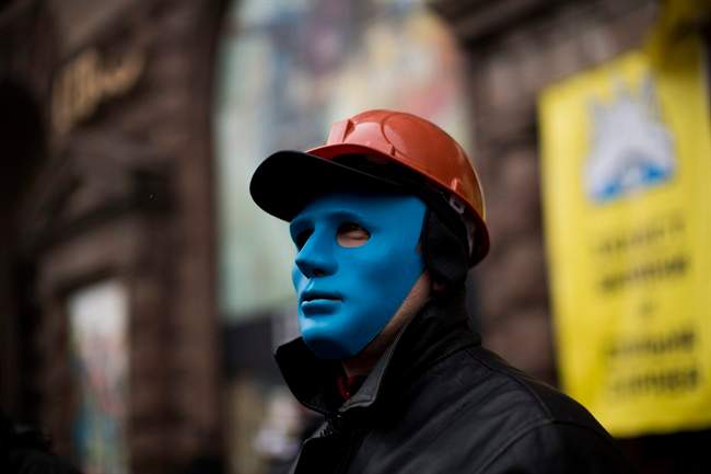 An anti-Yanukovych protester protects the entrance of a shop occupied by demonstrators still camped out on Kiev's Independence Square, the epicenter of the country's current unrest, Ukraine, Tuesday, Feb. 25, 2014. (AP Photo/Emilio Morenatti).