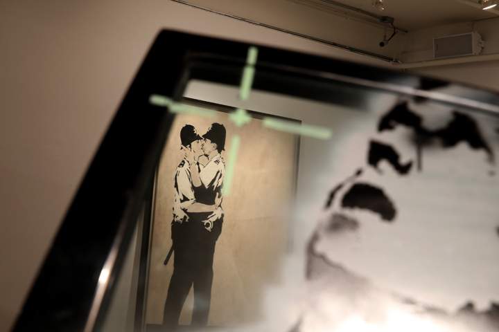 A piece of art titled "Kissing Coppers" by the artist Banksy is seen on display before it went to auction along with his "Crazy Horse Car Door" (foreground) piece at the Fine Art Auctions Miami Street Art Auction at LMNT on February 18, 2014 in Miami, Florida. 