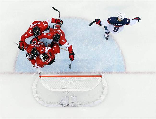 USA forward Zach Parise skates off the ice as Canadian players celebrate after a men's semifinal ice hockey game at the 2014 Winter Olympics, Friday, Feb. 21, 2014, in Sochi, Russia. Canada won 1-0 to advance to the gold medal game. (AP Photo/David J. Phillip ).
