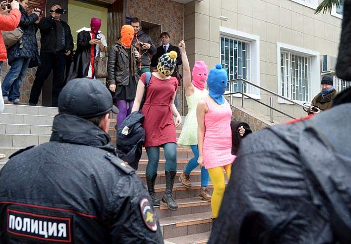 Wearing mask members of Russian punk group Pussy Riot, Nadezhda Tolokonnikova (R) and Maria Alyokhina (2dR) walk by journalists while leaving the police station of Adler, near Sochi, on February 18, 2014. 